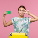 A woman displaying an EMI card along with a travel suitcase.